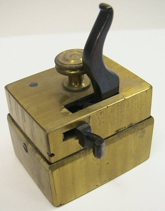 Unusual rectangular scarificator.  This piece is odd in the fusion of the later style box design and the earlier bar release mechanism.